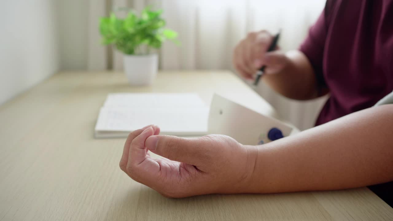 亚洲男人监测和检查她的血压，并在家里的客厅记录。常规自我医学检测视频素材