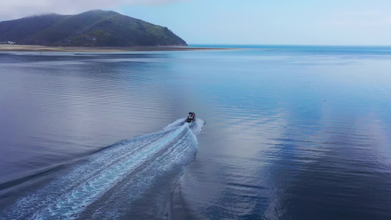 在一个明亮但暴风雨的日子里，动力船在平坦的大海上起航视频素材