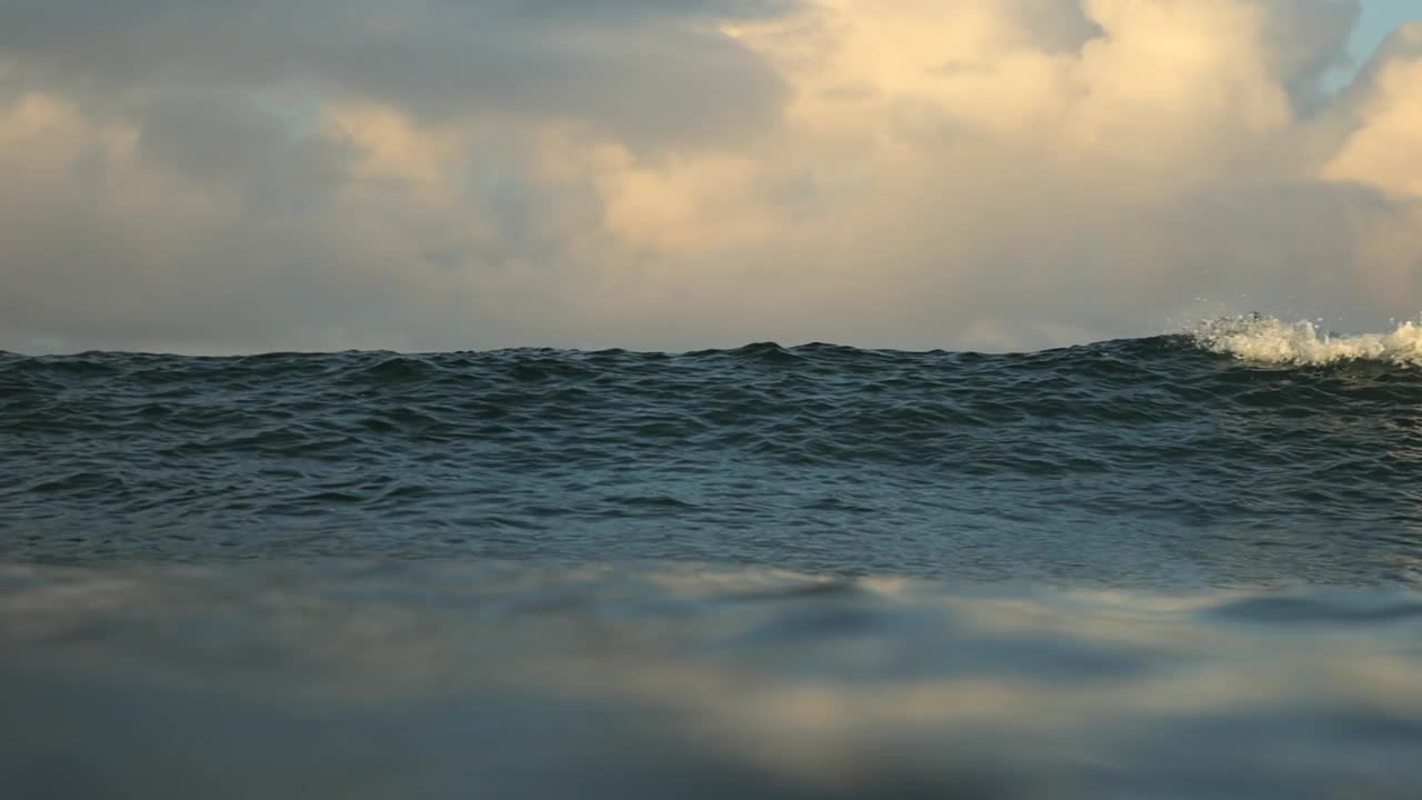 在日落时分，蓝色海洋中的海浪与多云的天空的慢动作平移镜头——印度尼西亚龙目岛视频素材