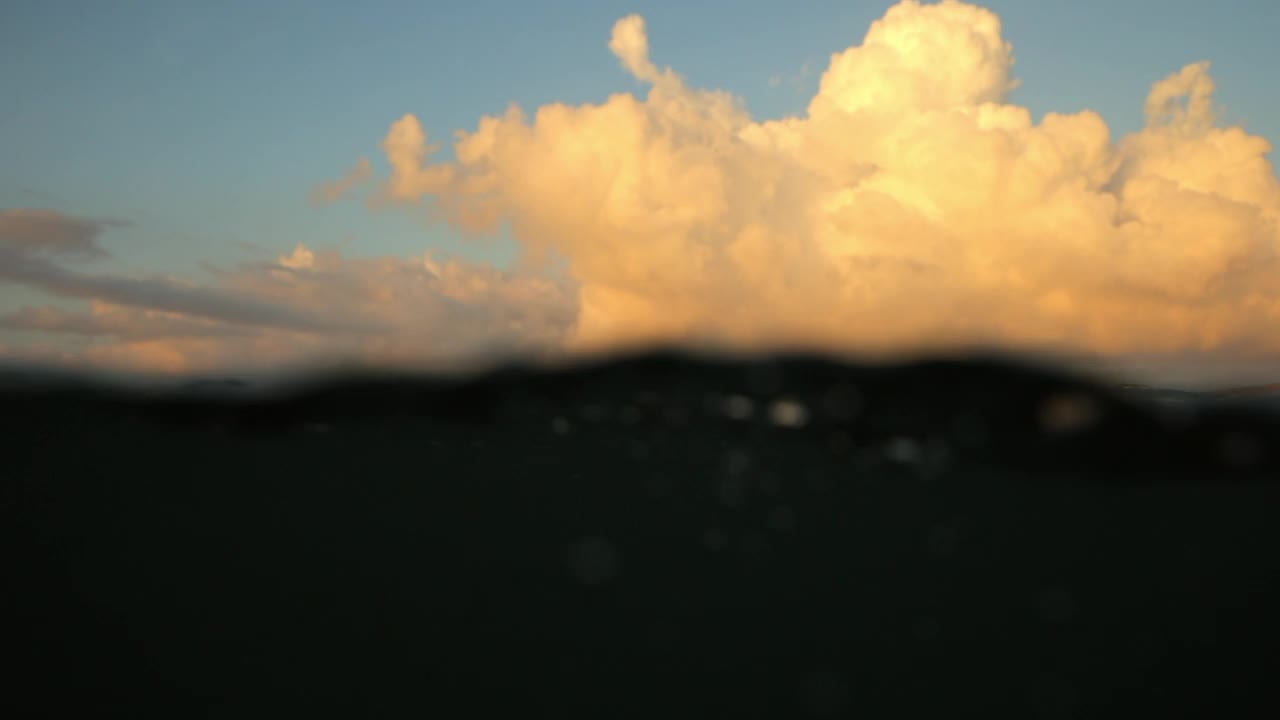 慢镜头的人冲浪冲浪板在波浪的大海对多云的天空在日落-龙目岛，印度尼西亚视频素材