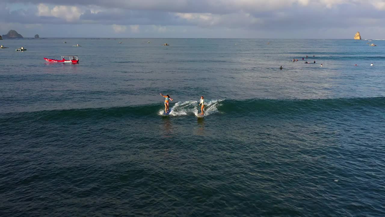 空中向后拍摄的女性在云层下的海浪上冲浪——印度尼西亚龙目岛视频素材