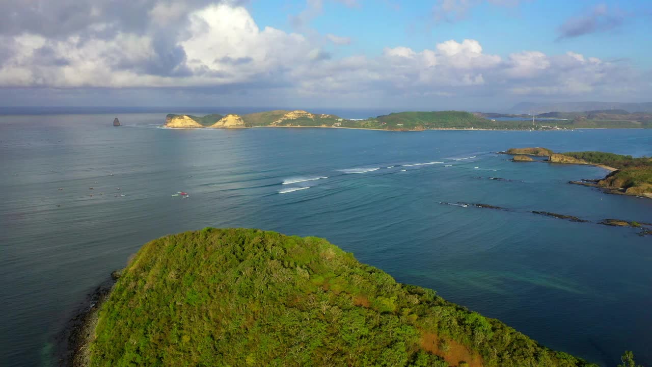 云下波浪海的空中平移美丽的观点，无人机在山上飞过绿色植物-龙目岛，印度尼西亚视频素材