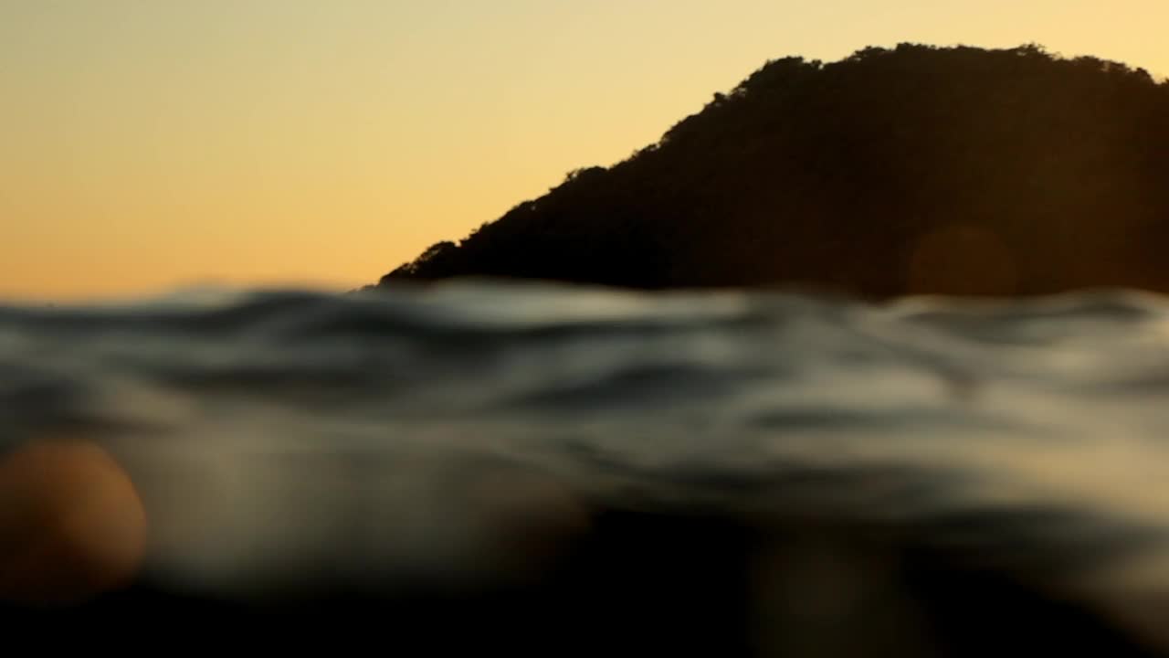 慢动作镜头的妇女游泳与冲浪板在海上海浪日落-龙目岛，印度尼西亚视频素材