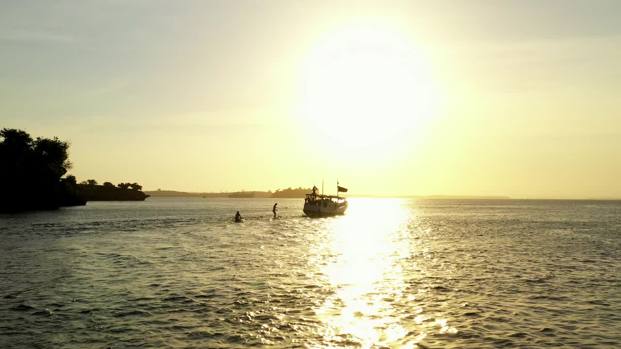 冲浪者在船后面冲浪的空中剪影，日落时无人机向前飞行-龙目岛，印度尼西亚视频素材