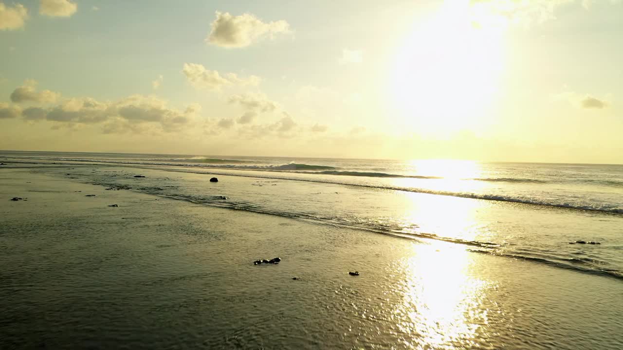 航拍:无人机拍摄的海浪冲向海岸，在日落时海滩上的天空-龙目岛，印度尼西亚视频素材