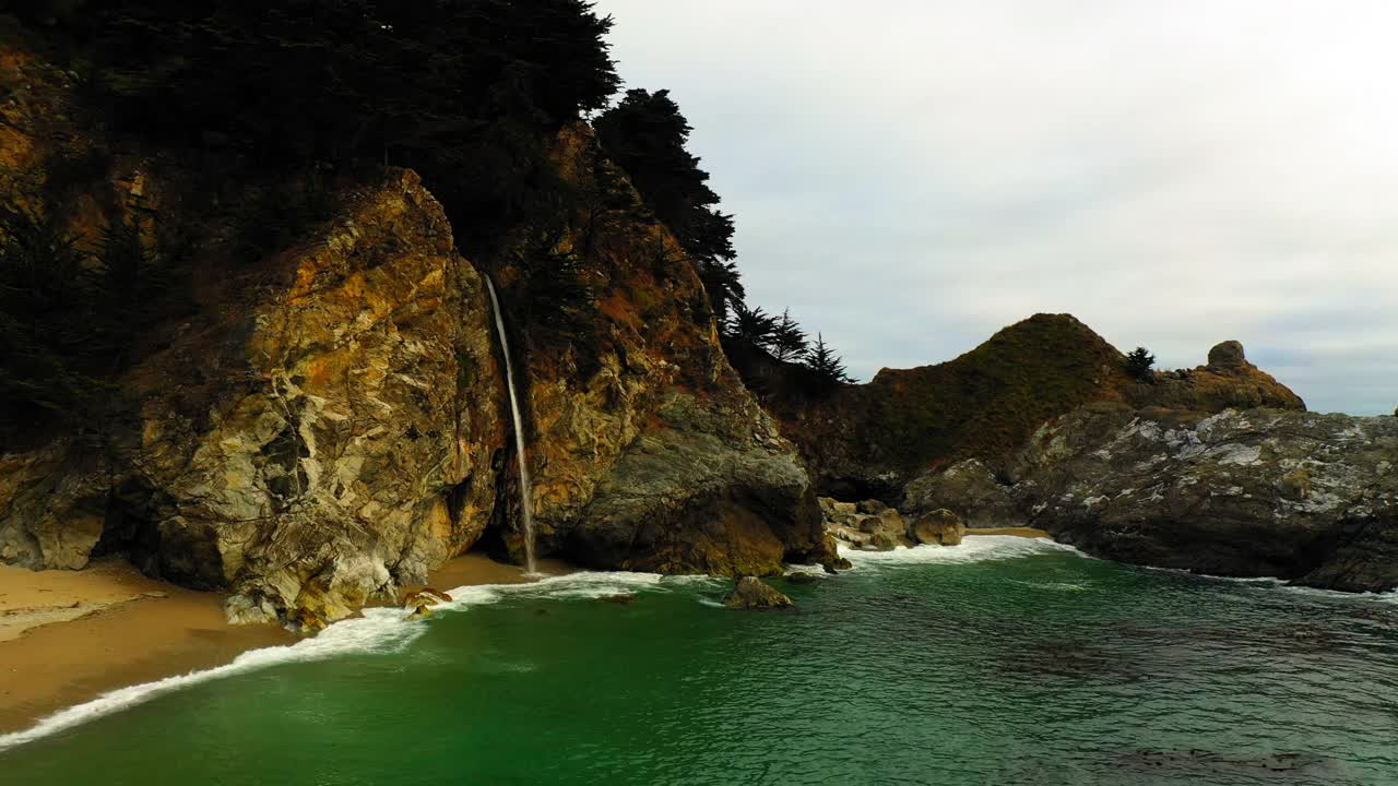 航拍拍摄美丽的瀑布从岩石岩层对天空在海滩的海岸线-旧金山，加利福尼亚视频素材