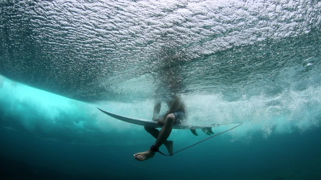 从深海海底看到的冲浪者悬挂在冲浪板上的腿的慢动作——马尔代夫的thulushoo视频素材