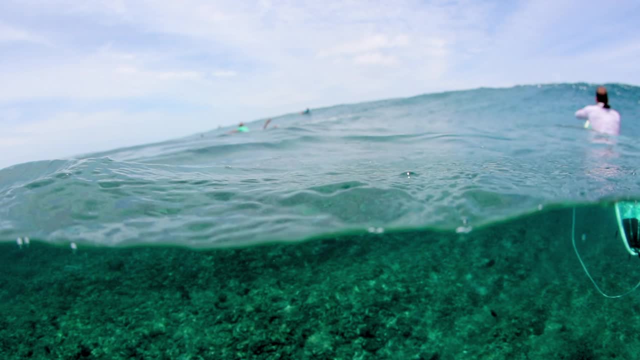 从海底度假时看到的人们带着冲浪板漂浮的慢动作镜头——马尔代夫的thulushoo视频素材