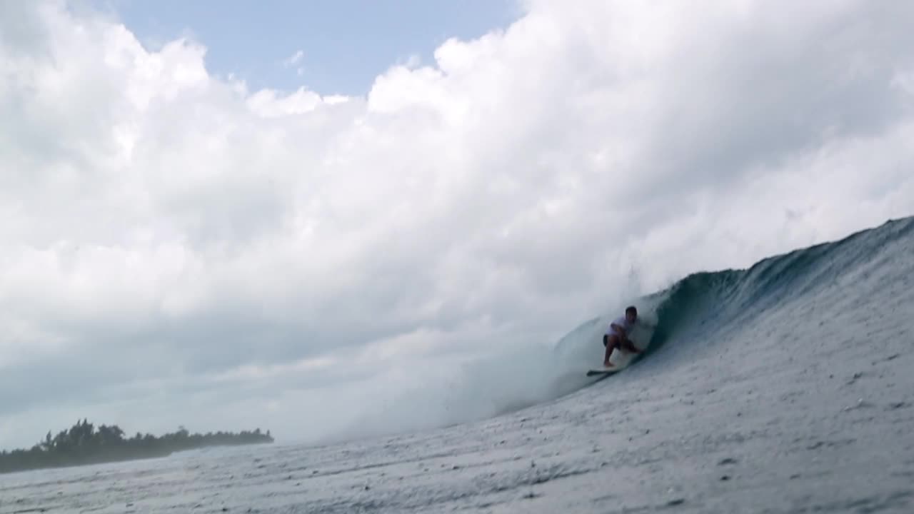 慢动作拍摄的冲浪者冲浪海浪在海上，而下雨- thulushoo，马尔代夫视频素材