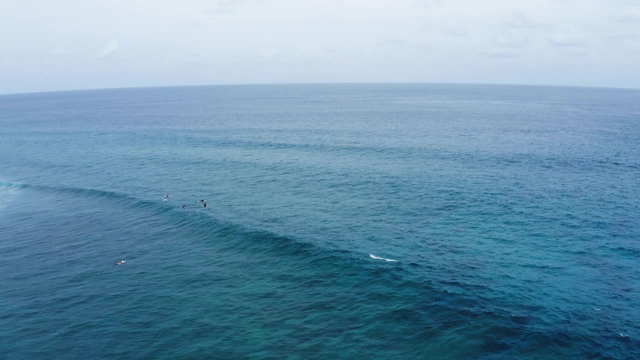 空中封锁拍摄的人们与冲浪板在海浪上游泳，在海上对着天空- thulushoo，马尔代夫视频素材