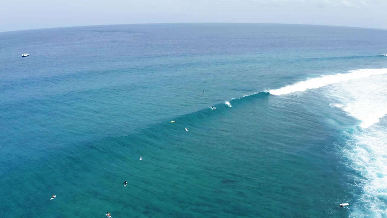 航拍的游客冲浪者在海浪中冲浪，无人机在阳光灿烂的日子里向后飞行-马尔代夫的thulushoo视频素材