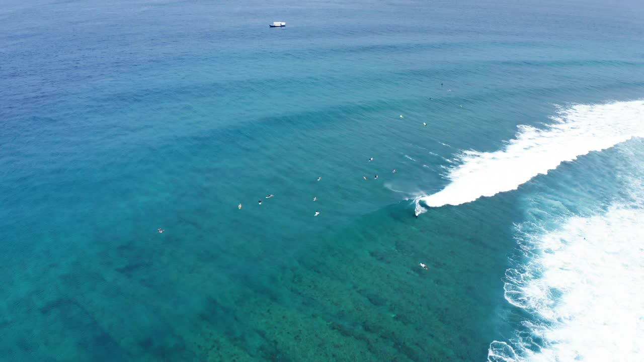 航拍的人们在波浪般的大海上冲浪，无人机在阳光灿烂的日子里向后飞行——马尔代夫的thulushoo视频素材