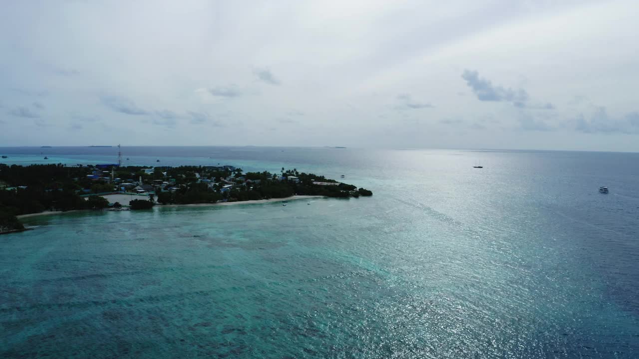 岛上结构的空中平移美景，无人机在云下飞越波浪海- thulushoo，马尔代夫视频素材