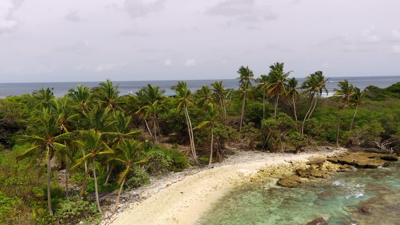 航拍海滩上的树木，人们在海里冲浪，无人机在天空中飞过岛屿-马尔代夫thulushoo视频素材