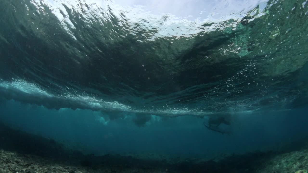 海底海浪与冲浪者的慢动作镜头，人在海上冲浪——马尔代夫视频素材