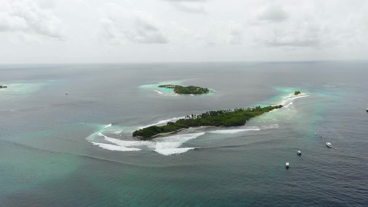 航拍拍摄海浪溅在岛上在海上对天空，无人机飞越船只在海洋- thulushoo，马尔代夫视频素材