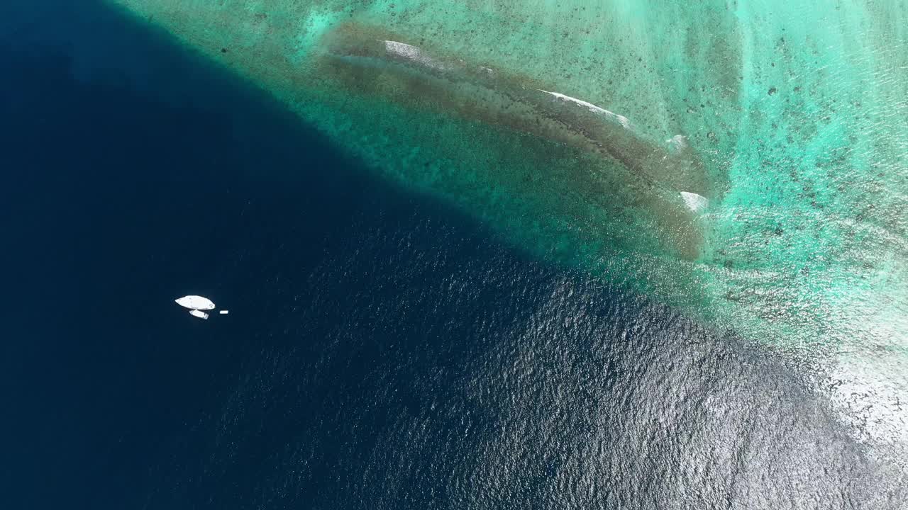 航拍俯视图的船只附近的波浪飞溅在环礁附近的海洋，无人机在晴天飞越海洋- thulushoo，马尔代夫视频素材