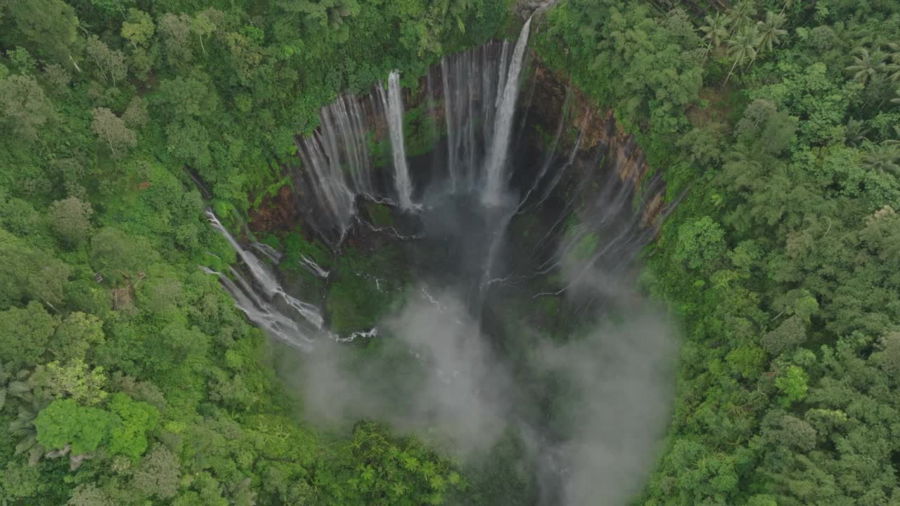 空中拍摄的风景著名梯级瀑布在岩层上流动，无人机在绿色森林上空飞行-印度尼西亚爪哇视频素材