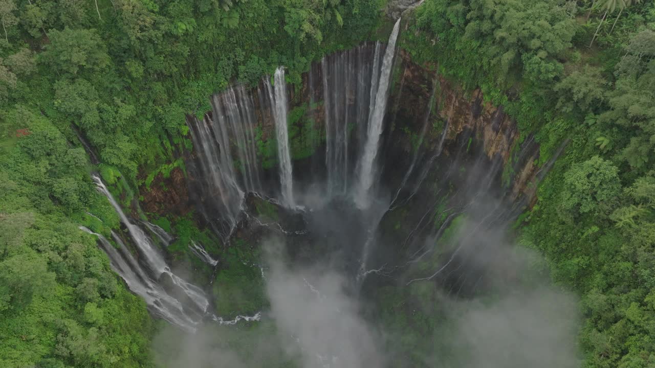 空中上升倾斜向下拍摄的巨大瀑布在岩石岩层中流动-爪哇，印度尼西亚视频素材