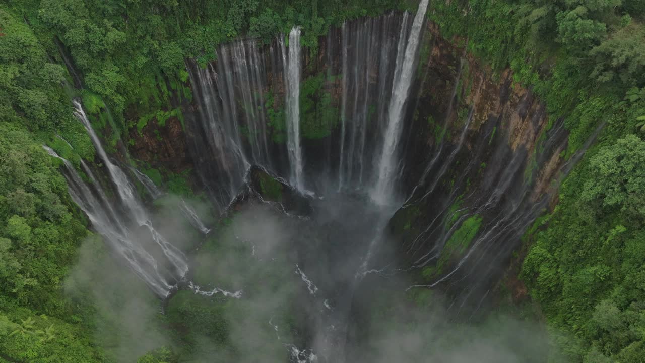 空中拍摄的Coban Sewu瀑布在岩层上流动，无人机在森林中飞过绿色的树木-爪哇，印度尼西亚视频素材