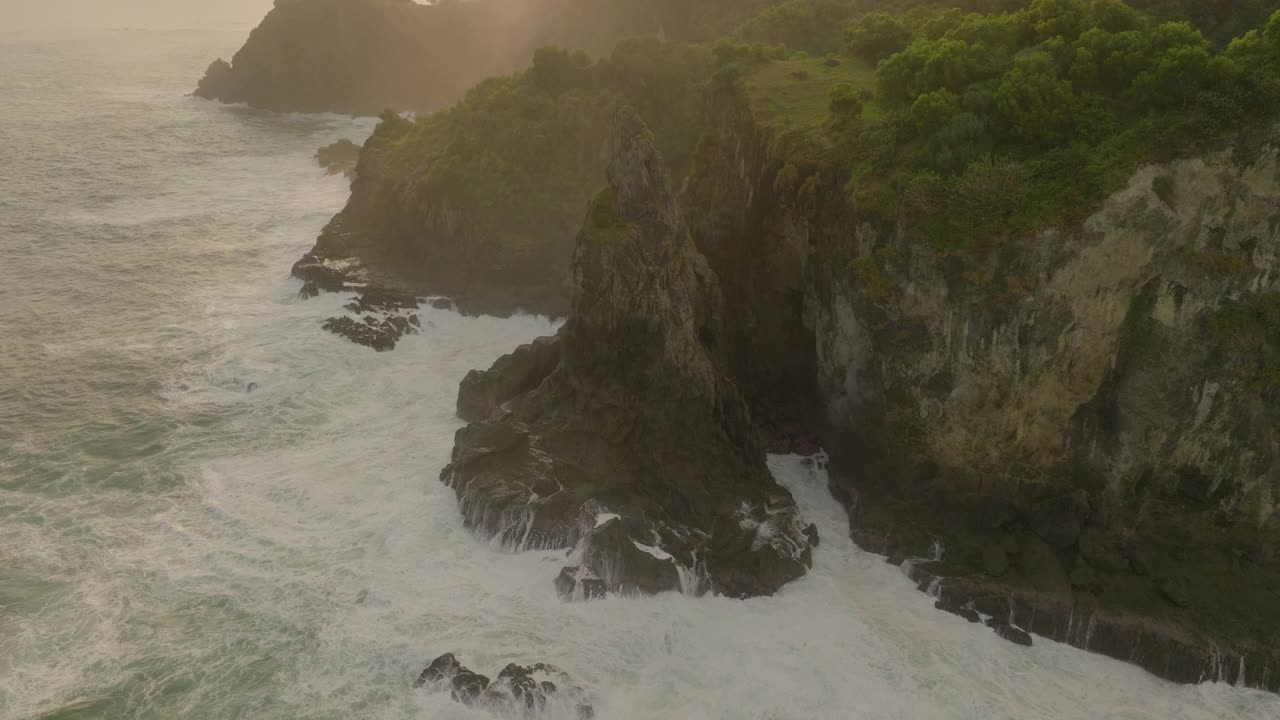 倾斜向上拍摄的海浪飞溅在岩石上对多云的天空-爪哇，印度尼西亚视频素材