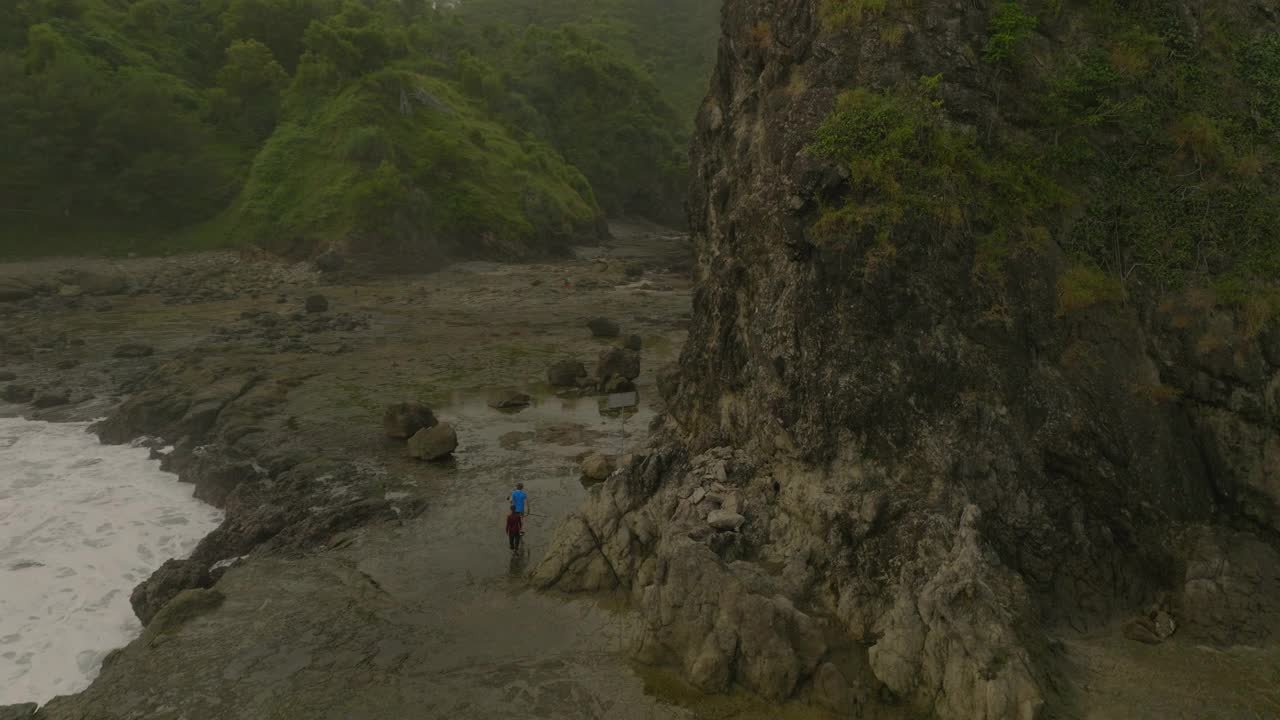 游客在度假期间走在岩石形成的湿地上的平移镜头-爪哇，印度尼西亚视频素材