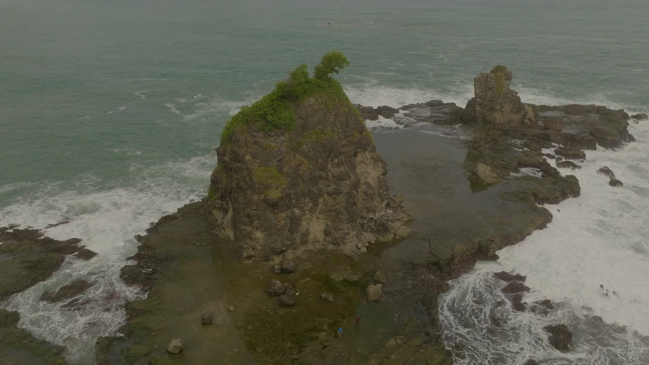 空中摇摄的游客探索潮湿的岩石形成在海上度假-爪哇，印度尼西亚视频素材