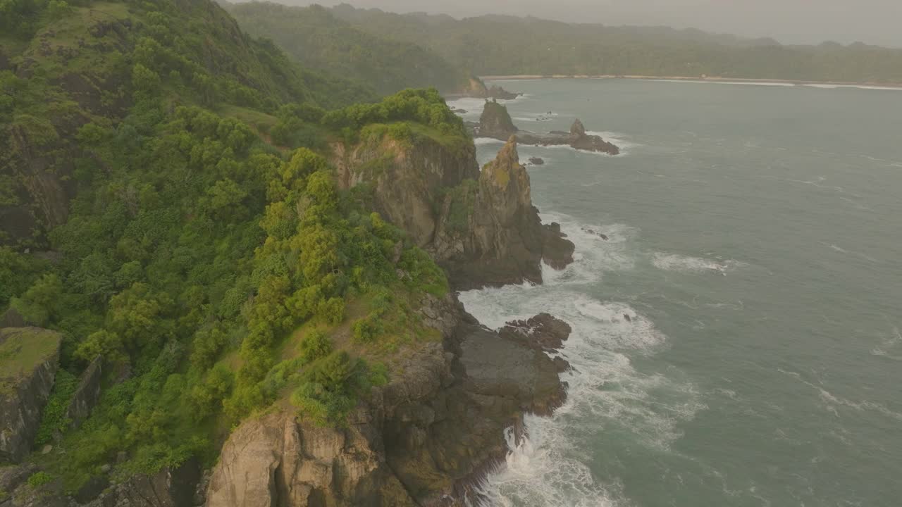 空中拍摄的天然岩层上的绿色植物，无人机在海上的海浪上向前飞行-爪哇，印度尼西亚视频素材