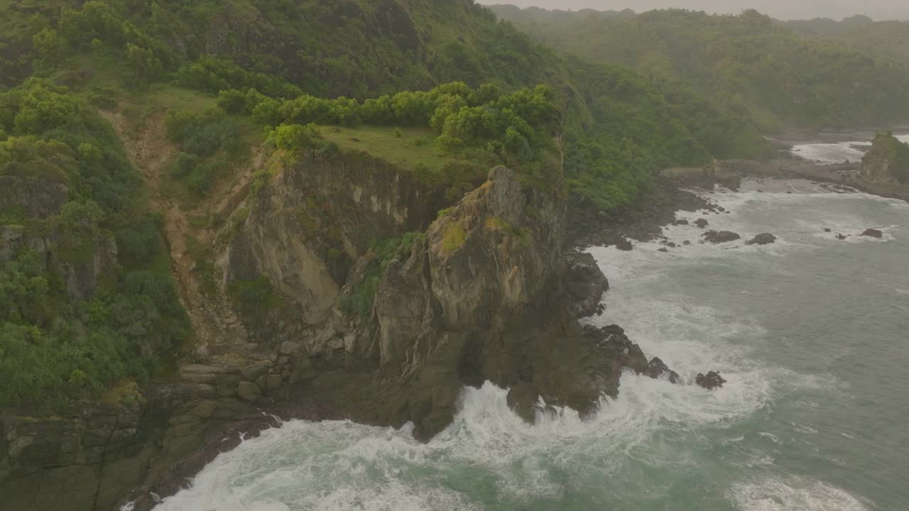 空中平移拍摄的绿色植物在自然山脉对天空，无人机在日落期间飞越海洋-爪哇，印度尼西亚视频素材