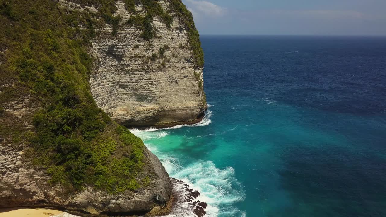 空中无人机飞越岩石悬崖，天堂岛努萨佩尼达。海浪拍打着石头和岩石。水是翡翠，深蓝和绿色。蓝绿色印度洋的美丽景色。印尼视频下载