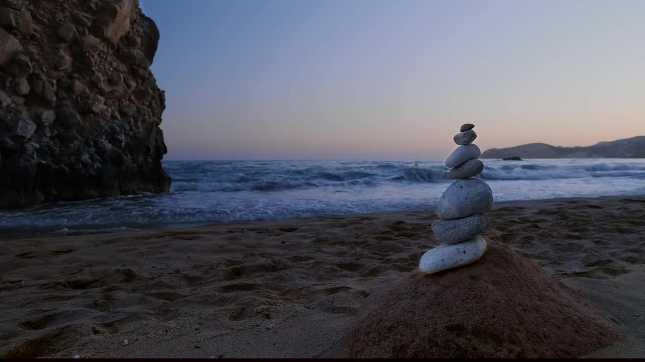 日落时分海滩上的石头。背景是岩石和海浪。禅的概念，放松，冥想，脆弱视频素材