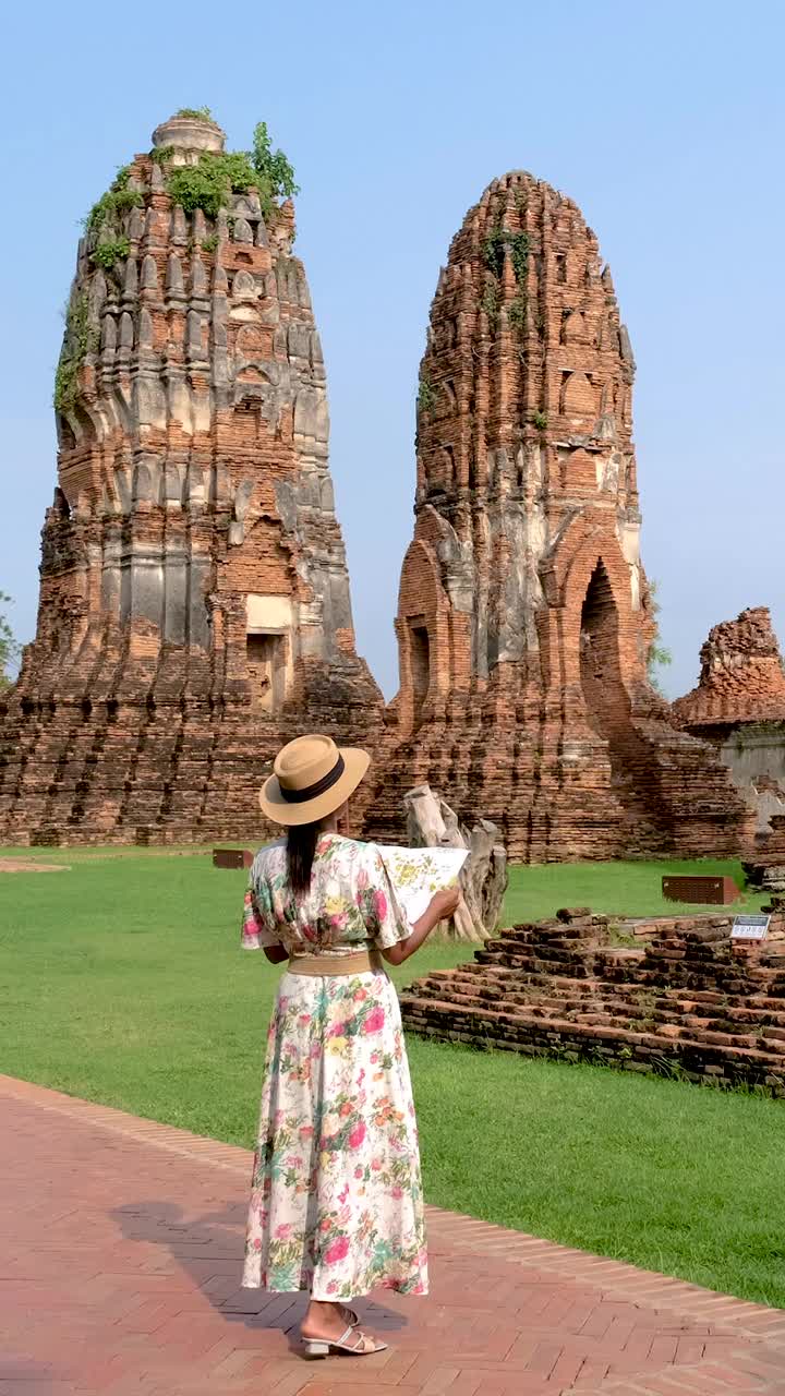 亚洲妇女手里拿着旅游地图，看着泰国大城府的废墟和宝塔视频素材