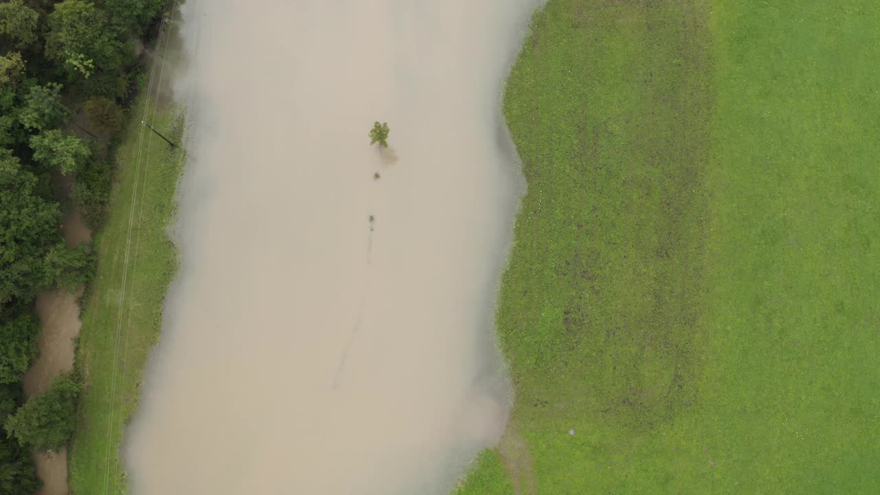 河水漫过河岸，淹没了田野，洪水逼近房屋，航拍视频素材