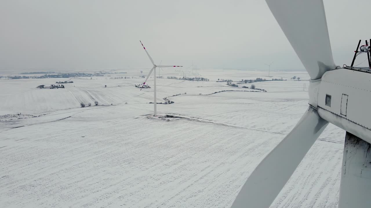 大型风力发电机近距离叶片旋转，在寒冷的冰天雪地的冬天产生清洁的生态电力视频素材