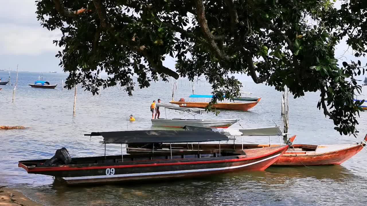 阳光明媚的日子里，渔船驶离海滩视频素材