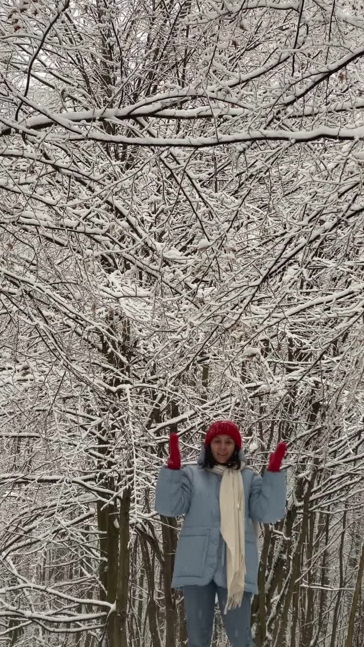 快乐的女人在森林里摇着被雪覆盖的树枝视频素材