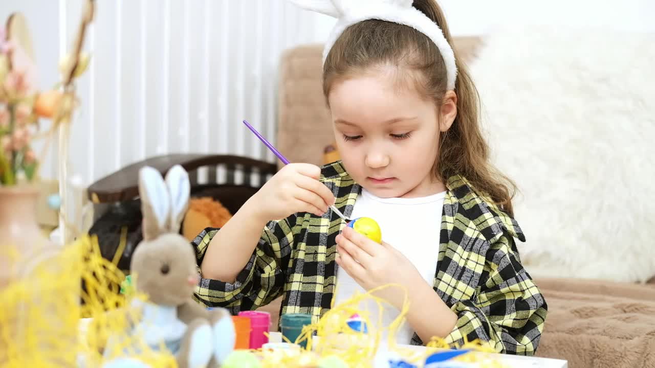 小女孩染复活节彩蛋。孩子为复活节狩猎画彩蛋。用鲜花、篮子和兔子来庆祝春节。视频素材