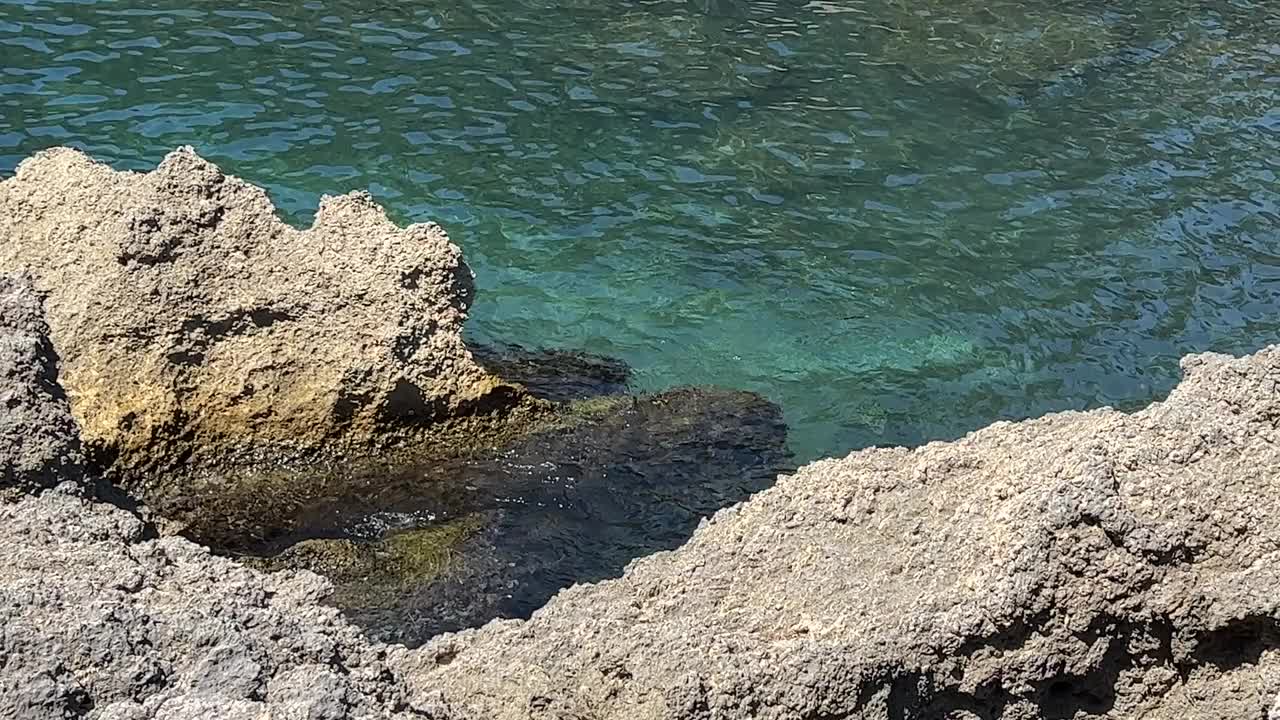 海边的岩石在碧绿的海水中清澈。视频素材