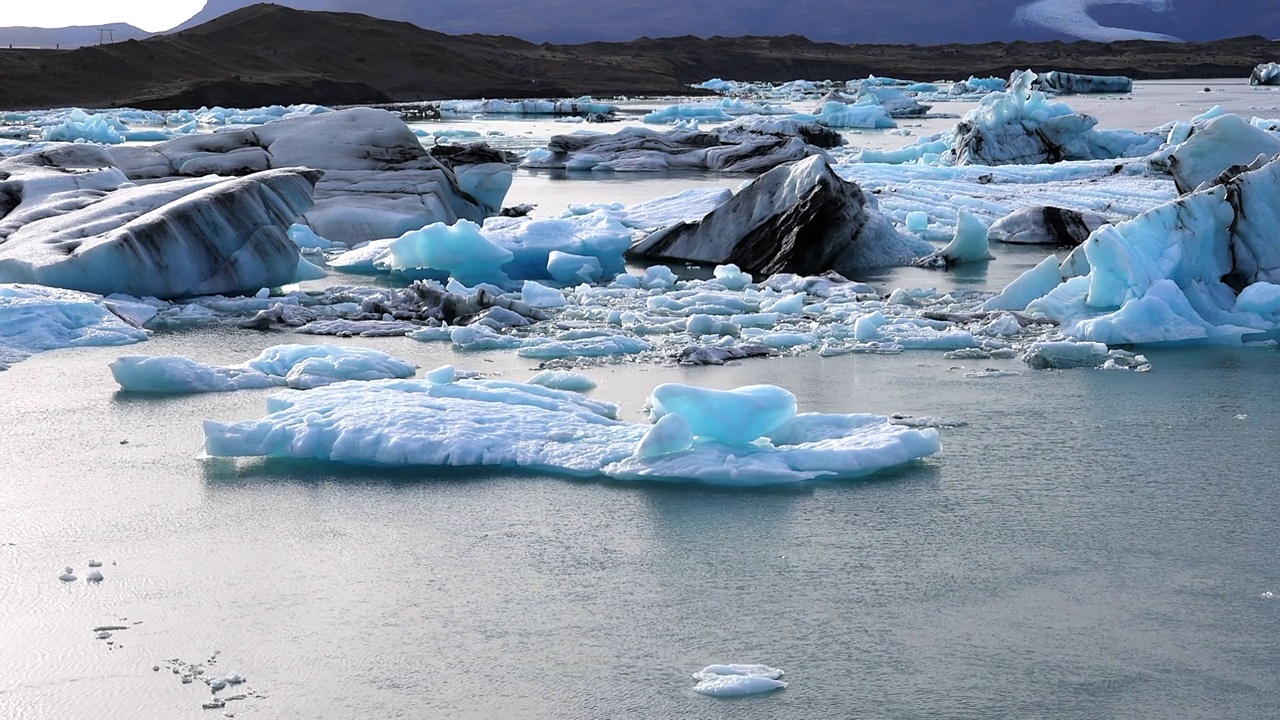 冰山从Jokulsarlon冰川泻湖漂浮到钻石海滩和北大西洋，随着退潮，冰岛。视频下载