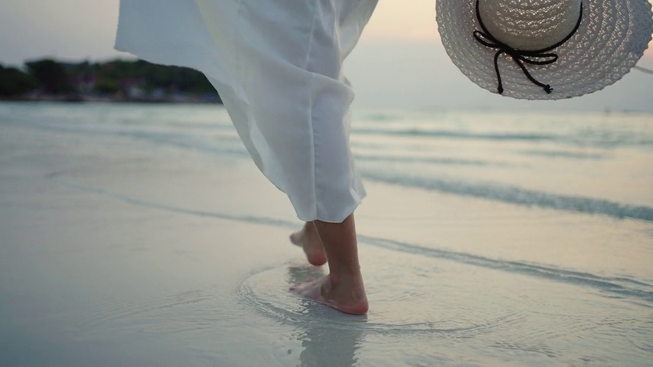 4K亚洲女子走在热带岛屿海滩上的夏日日落视频素材