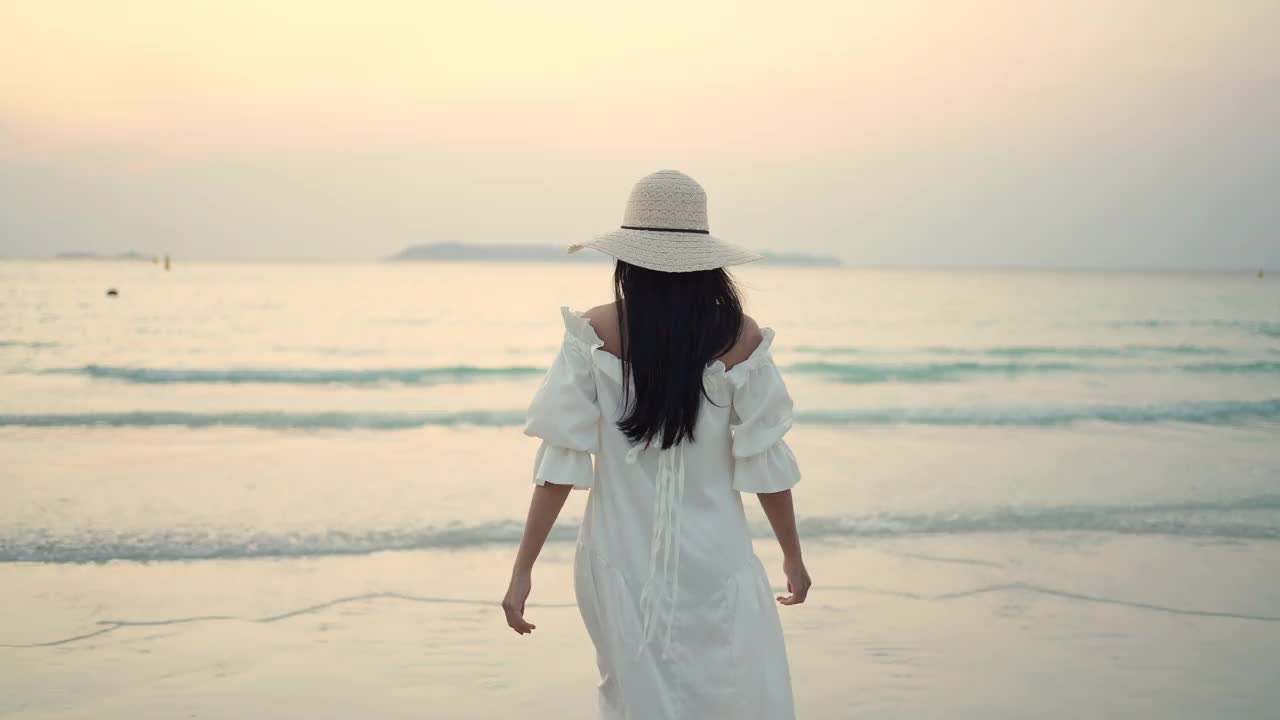 4K年轻的亚洲女子走在热带岛屿海滩上，夏日日落视频素材