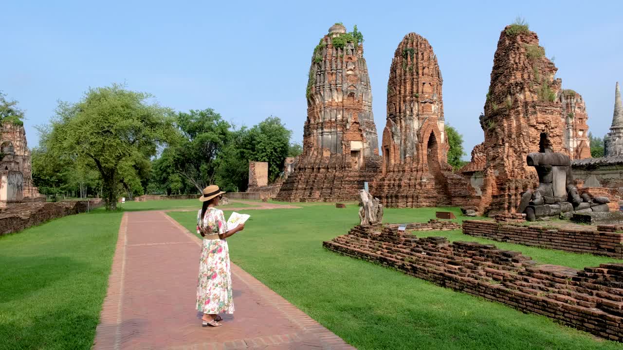 亚洲妇女手里拿着旅游地图，看着泰国大城府的废墟和宝塔视频素材