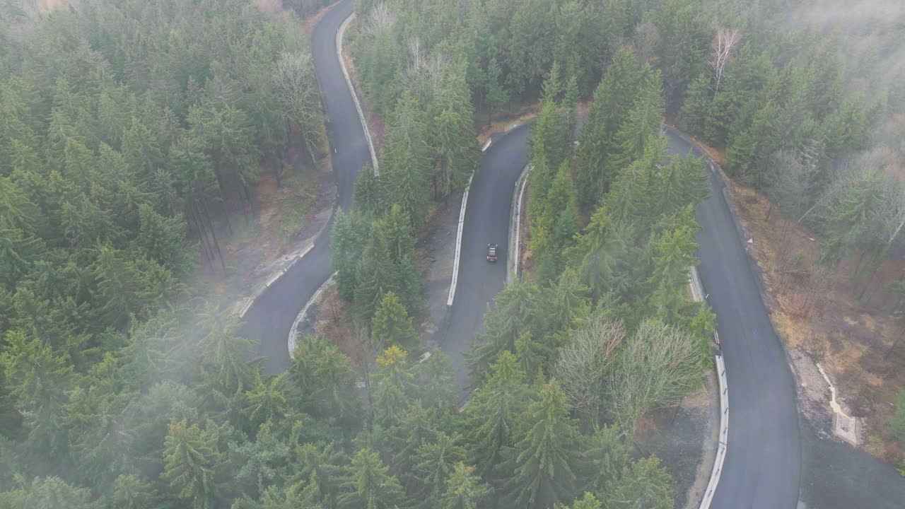 云雾天，空中拍摄的山路，山上有树。美丽秋林的晨雾。视频下载