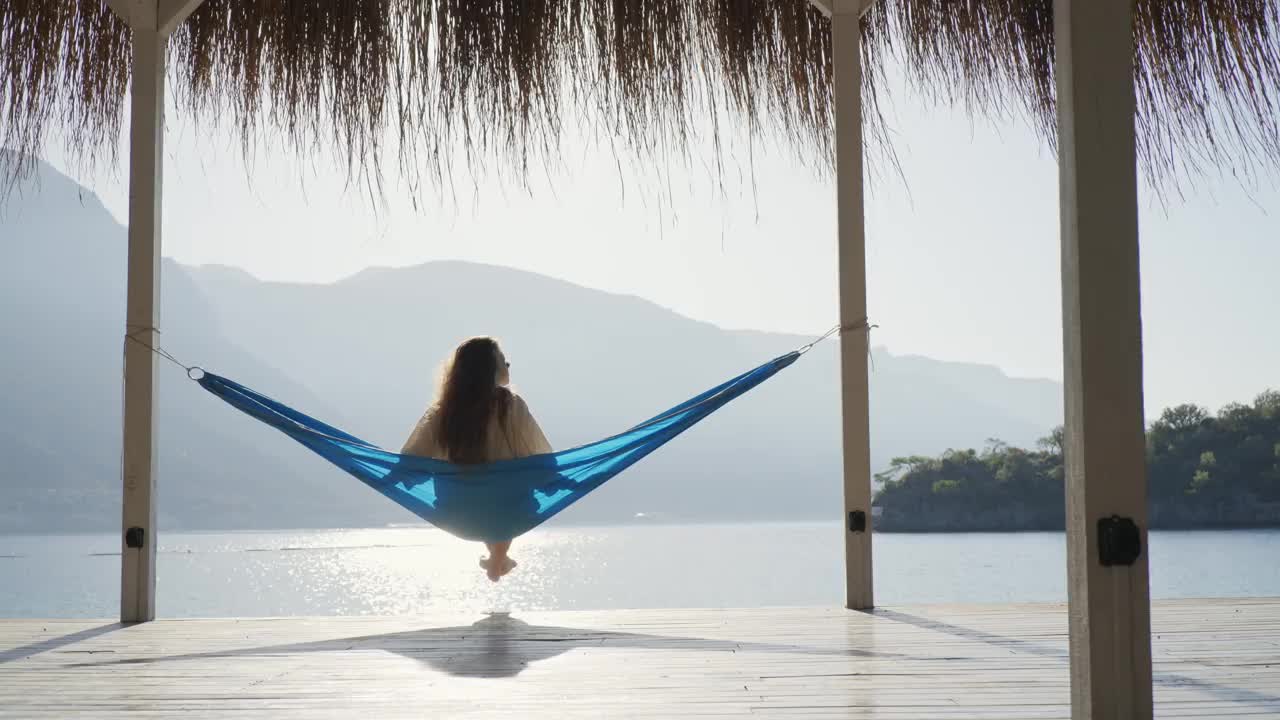 女人在沙滩上的吊床上放松。视频素材