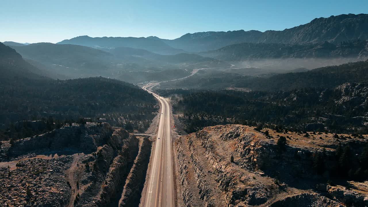 公路在山间映衬着湛蓝晴朗的天空。运输的概念。航拍无人机视频。视频素材