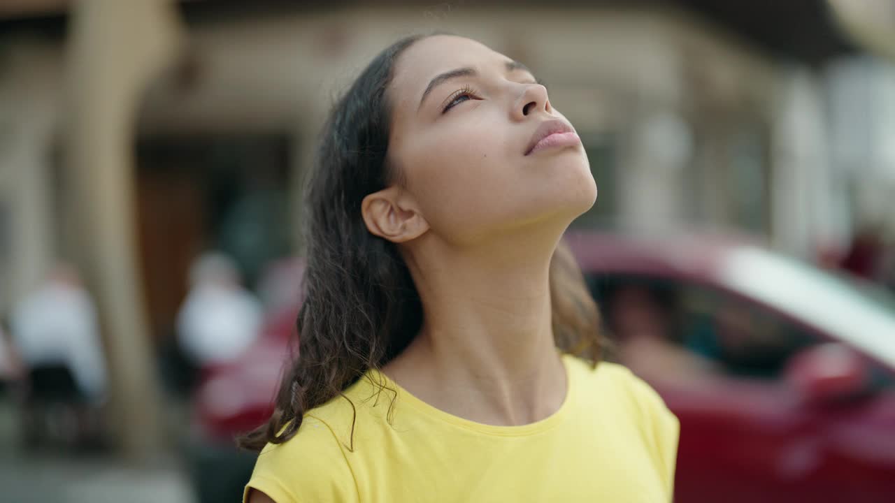 年轻的非裔美国妇女微笑自信地看着天空在街道视频素材