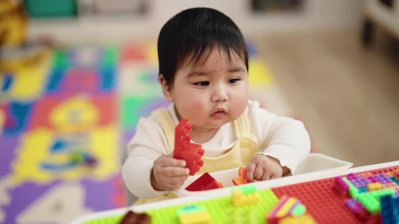 可爱的西班牙宝宝坐在幼儿园的桌子上玩积木视频素材