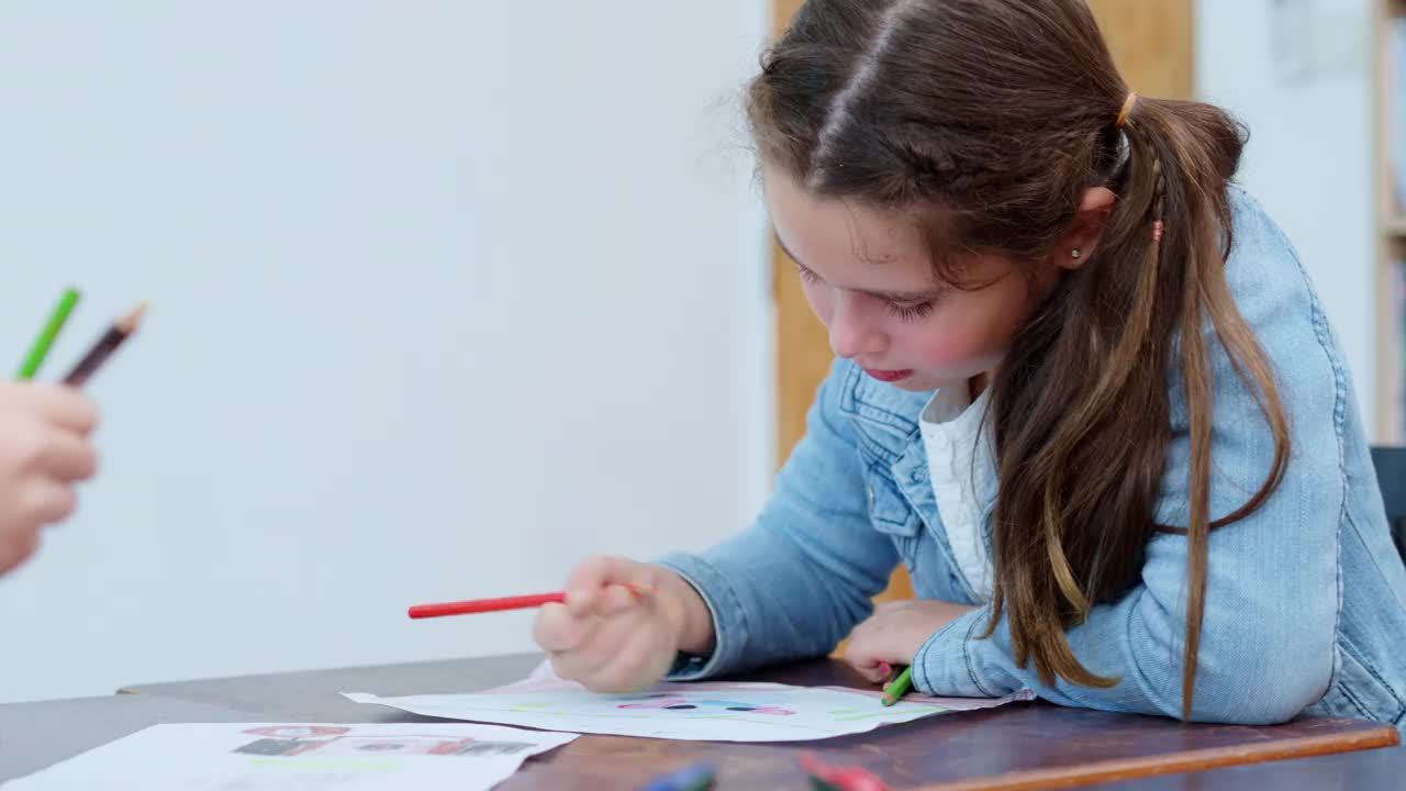 白人小学女生在美术课上学习时在纸上画画。视频素材