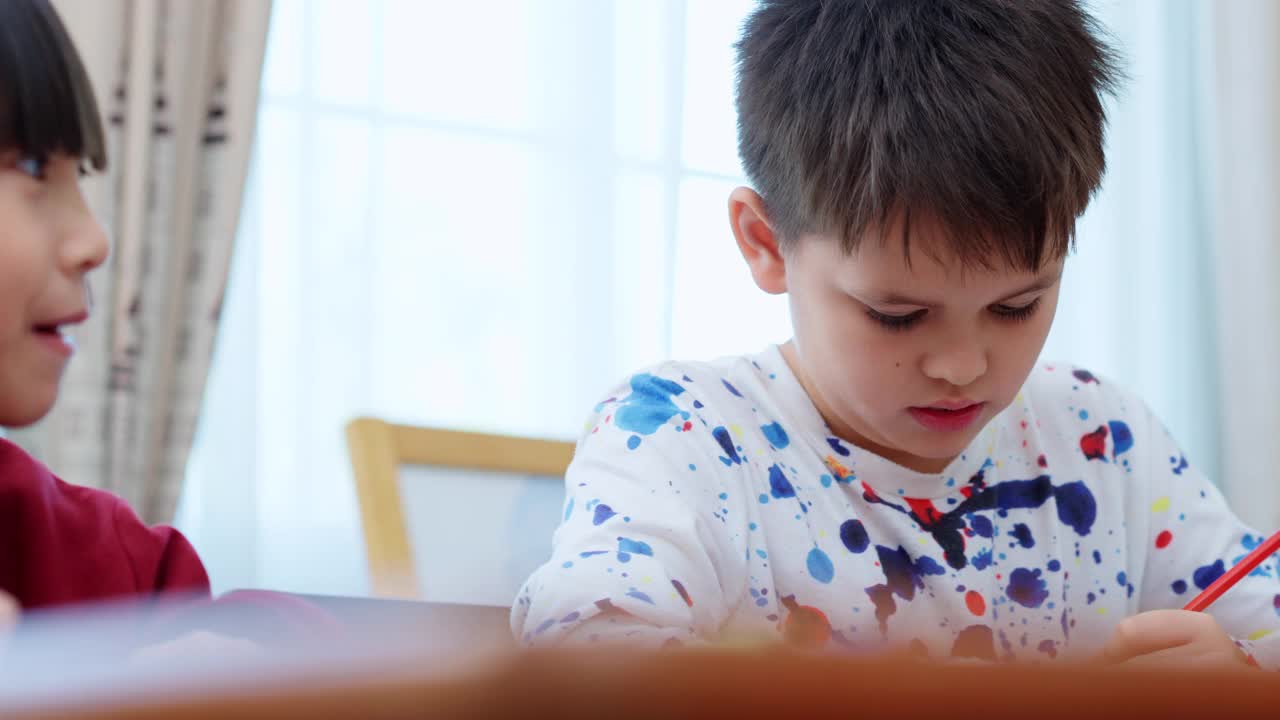 两个多种族的小学生在美术课上学习时在纸上画画的特写。视频素材