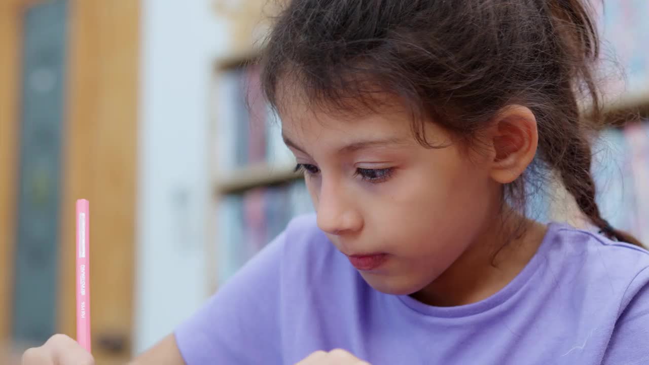 白人小学女生与多种族朋友在美术课上学习时在纸上画画的特写。视频素材